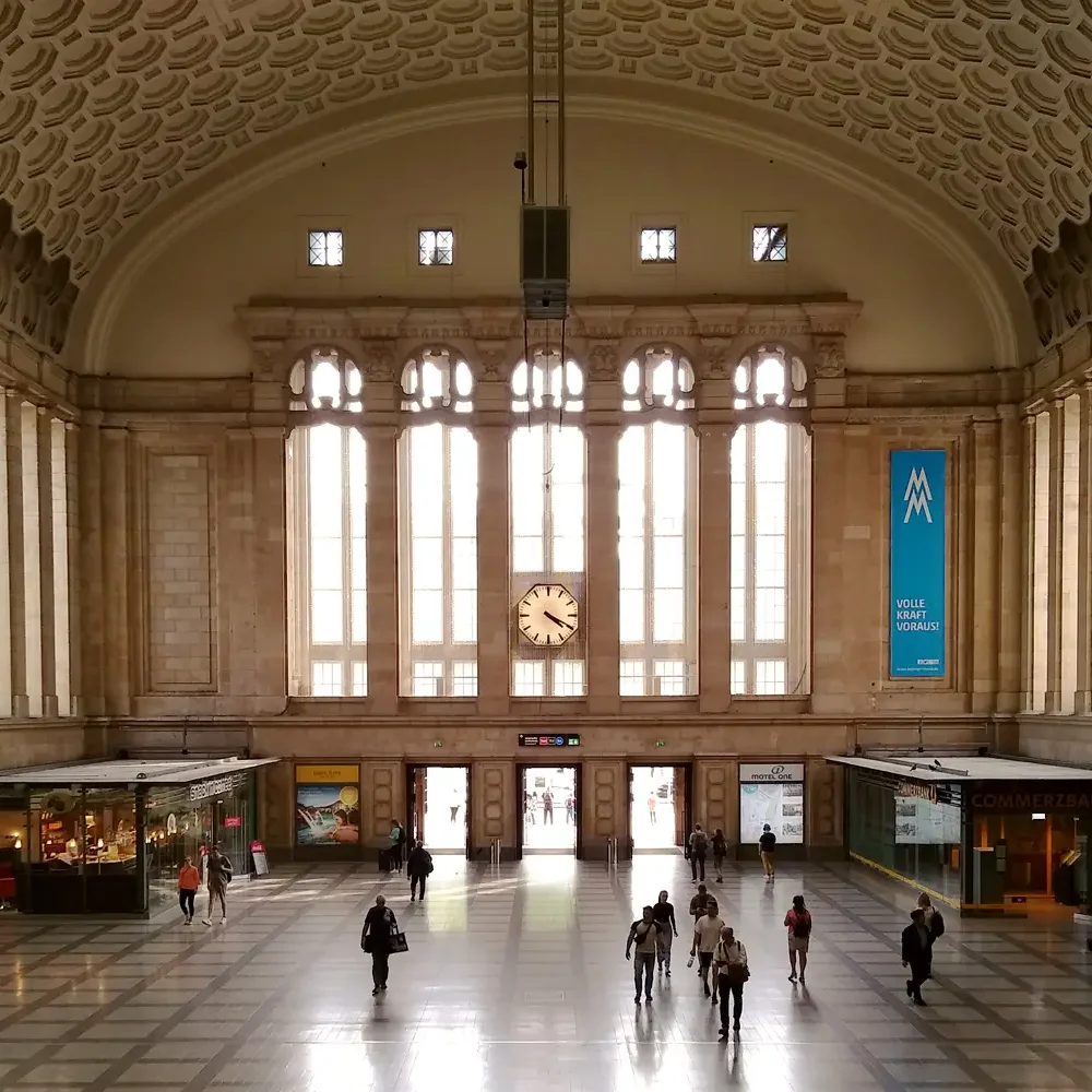 Innenansicht des Leipziger Hauptbahnhofs mit Passanten.
