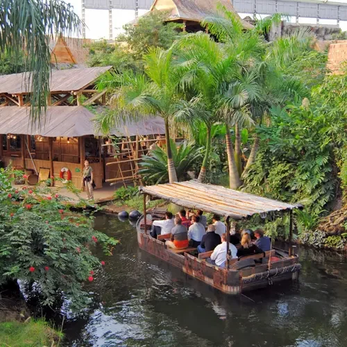 Blick in die Tropenhalle des Zoos mit Urwaldfluss und Besuchern.