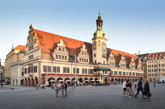 Der Leipziger Markt mit dem Alten Rathaus und Passanten im Abendlicht.