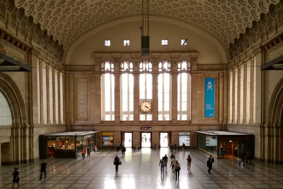 Blick in die weitläufige Osthalle des Hauptbahnhofs mit Passanten im Nachmittagslicht.