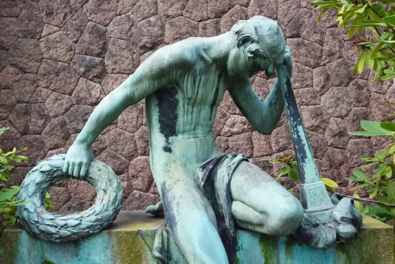 Verwitterte Jünglingsfigur auf einem historischen Grabmal.